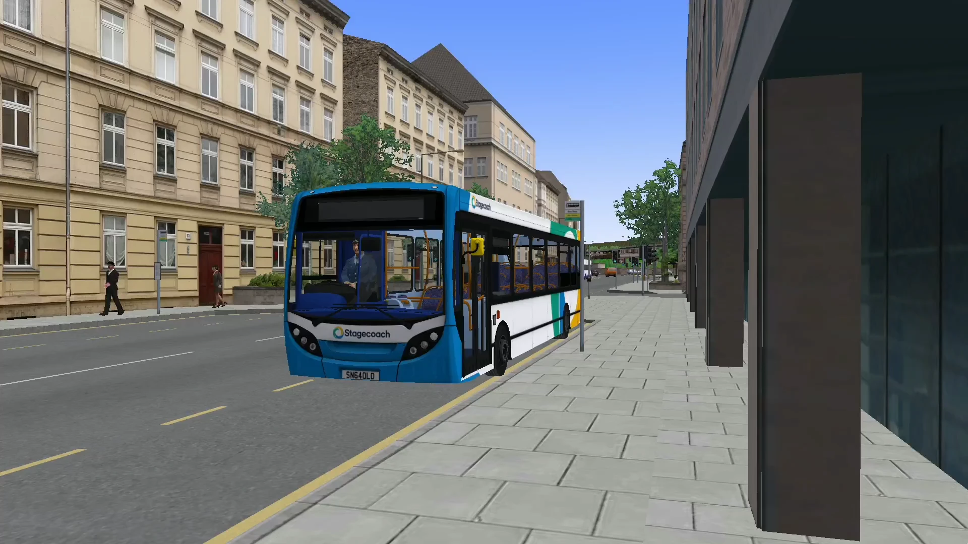 A Stagecoach Enviro 200 waiting at a bus stop on a city street, with pedestrians on the pavement.